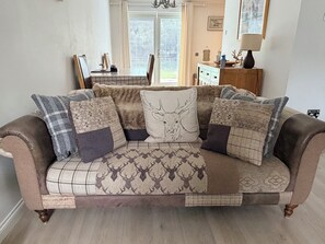 A sofa with patterned cushions and a decorative pillow with a deer design. - Glenmore Lodge | Luxury Braemar Highland Retreat | Walk to Village | Sleeps 6 (Braemar)