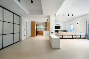 A modern interior with a kitchen, living area, and a large sliding door. - Luxury Beachfront Villa with infinity Pool & Breathtaking Sea Views (Mpenitses)