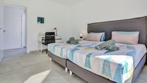 A bedroom with a bed, a desk, a chair, and a nightstand.
