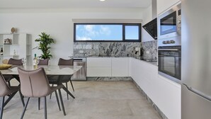 A modern kitchen with white cabinets, a marble backsplash, and stainless steel appliances.