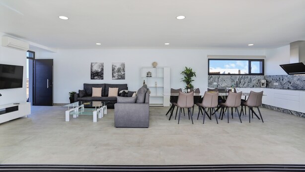 A modern living room with a sofa, coffee table, TV, and dining area with chairs and a table.