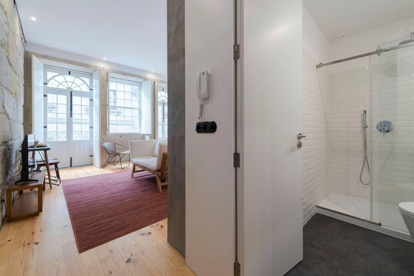 A modern bathroom with a glass shower enclosure and a white tiled wall.