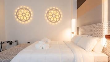 Ein Hotelzimmer mit einem ordentlich bezogenen Bett, zwei Wandleuchten und einem gemusterten Kopfteil.