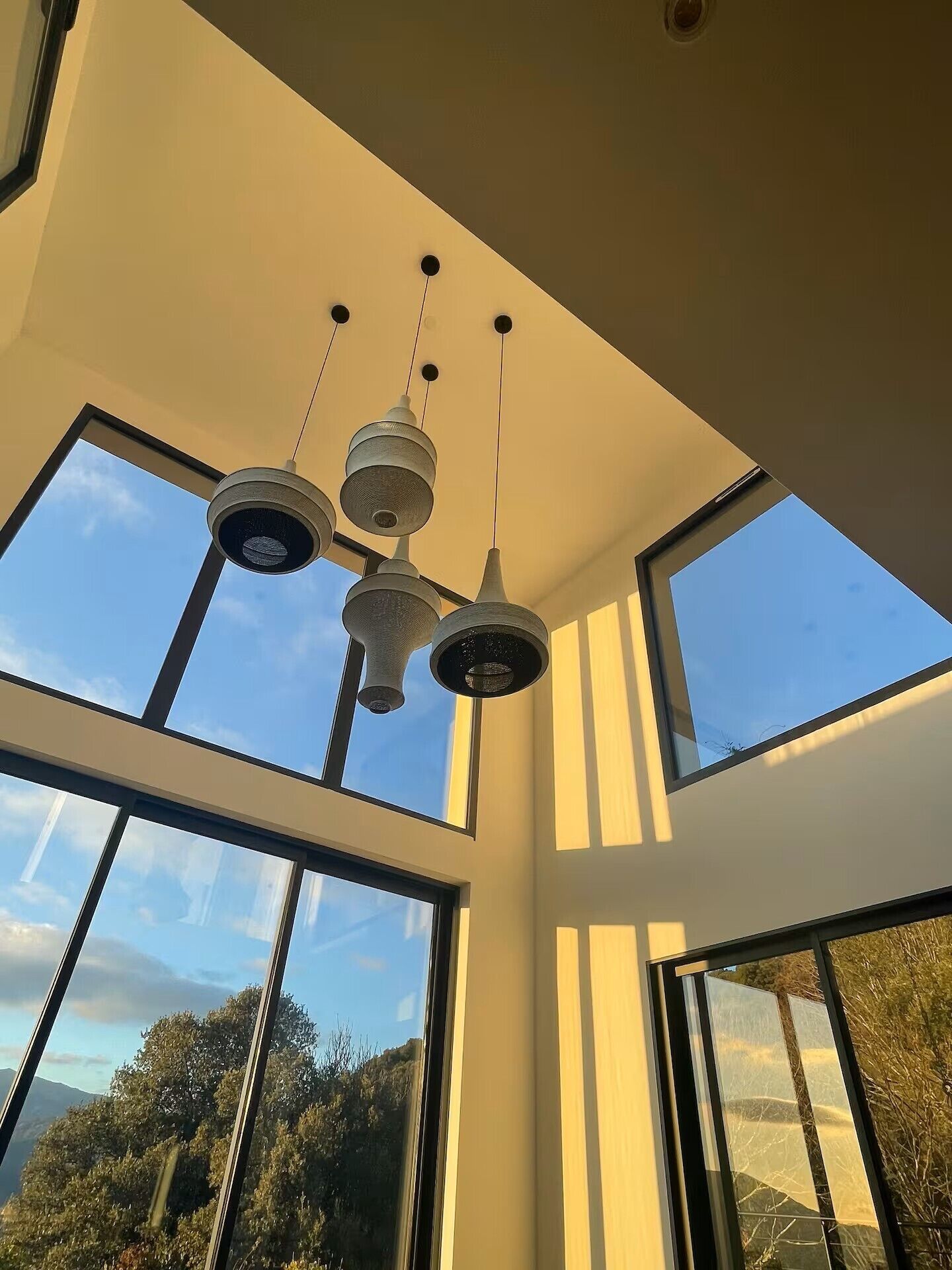 A room with large windows, a ceiling light fixture, and a view of the outdoors.