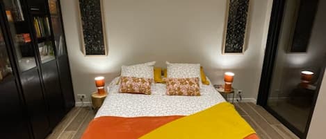 Ein Schlafzimmer mit einem Bett, zwei Nachttischlampen, einem Nachttisch und einem großen Kleiderschrank sowie einem großen Fenster.