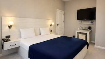 A modern bedroom with a large bed, bedside lamps, a flat-screen TV, and a desk with a coffee maker.