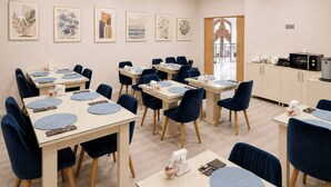 A dining area with tables set for four, blue chairs, and framed artwork on the walls. - Central Way Baku (Baku)