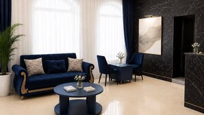 A modern living room with a dark blue sofa, a round coffee table, and a black marble accent wall. - Central Way Baku (Baku)