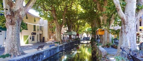 A canal lined with trees and benches, with buildings on one side and a bicycle parked on the other.