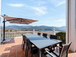 An outdoor patio with a table and chairs, a large umbrella, and a scenic mountain view. - Casa Juan for 8 people, with a private pool, a patio with a grill, and a magnificent lake view (Viñuela)