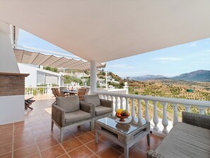 A terrace with wicker furniture, a table with a fruit bowl, and a view of vineyards and mountains. - Casa Juan for 8 people, with a private pool, a patio with a grill, and a magnificent lake view (Viñuela)