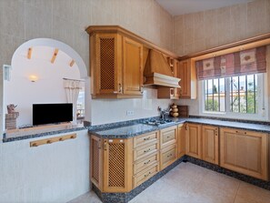 A kitchen with wooden cabinets, a granite countertop, and a window with a view. - Casa Juan for 8 people, with a private pool, a patio with a grill, and a magnificent lake view (Viñuela)