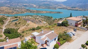 A residential area with houses, a road, and a lake in the background. - Casa Juan for 8 people, with a private pool, a patio with a grill, and a magnificent lake view (Viñuela)