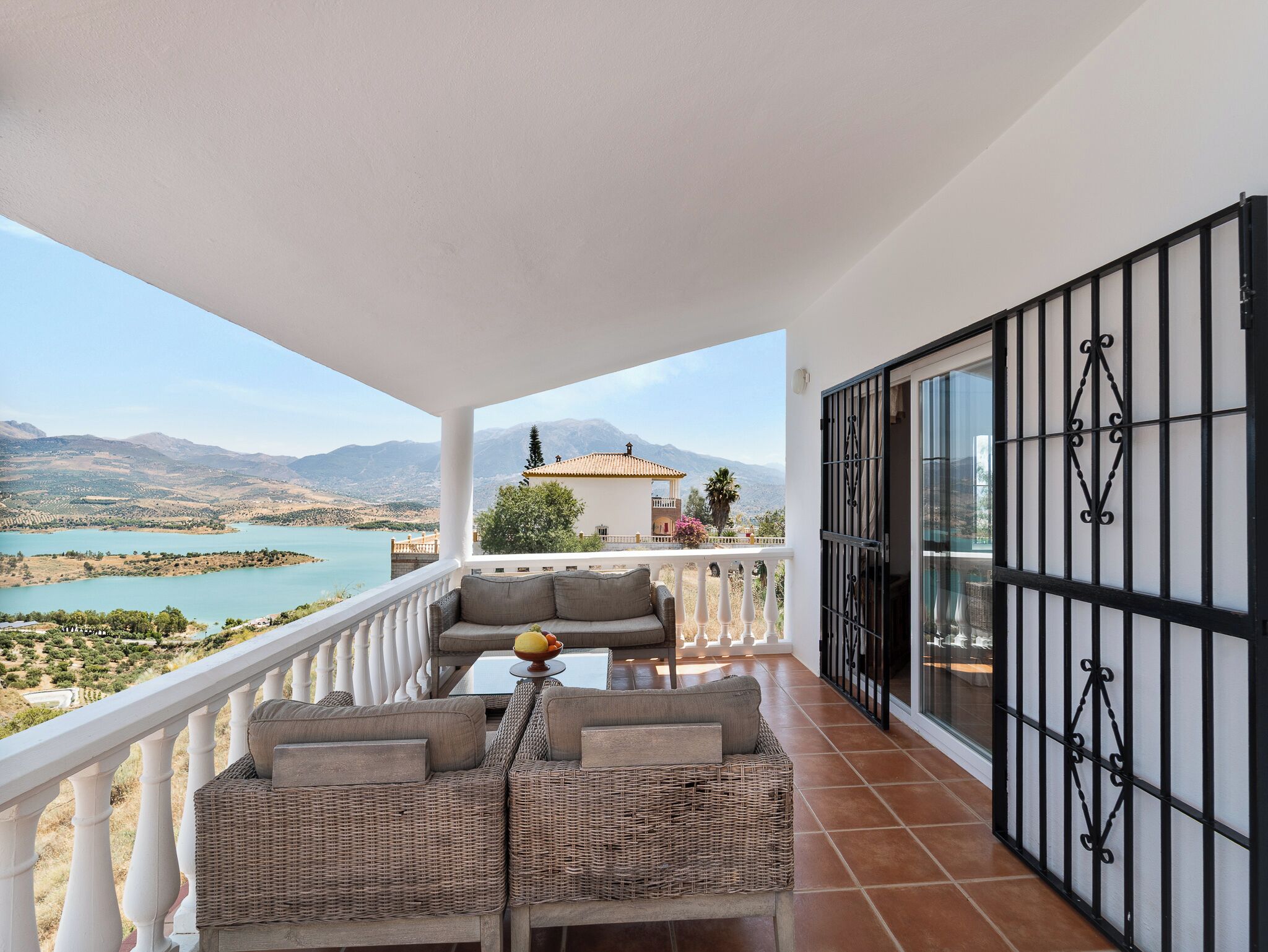 Un balcon avec vue sur un lac et des montagnes, aménagé avec un canapé et une table.