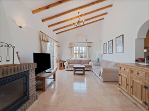 A living room with a fireplace, a sofa, a coffee table, and a television. - Casa Juan for 8 people, with a private pool, a patio with a grill, and a magnificent lake view (Viñuela)