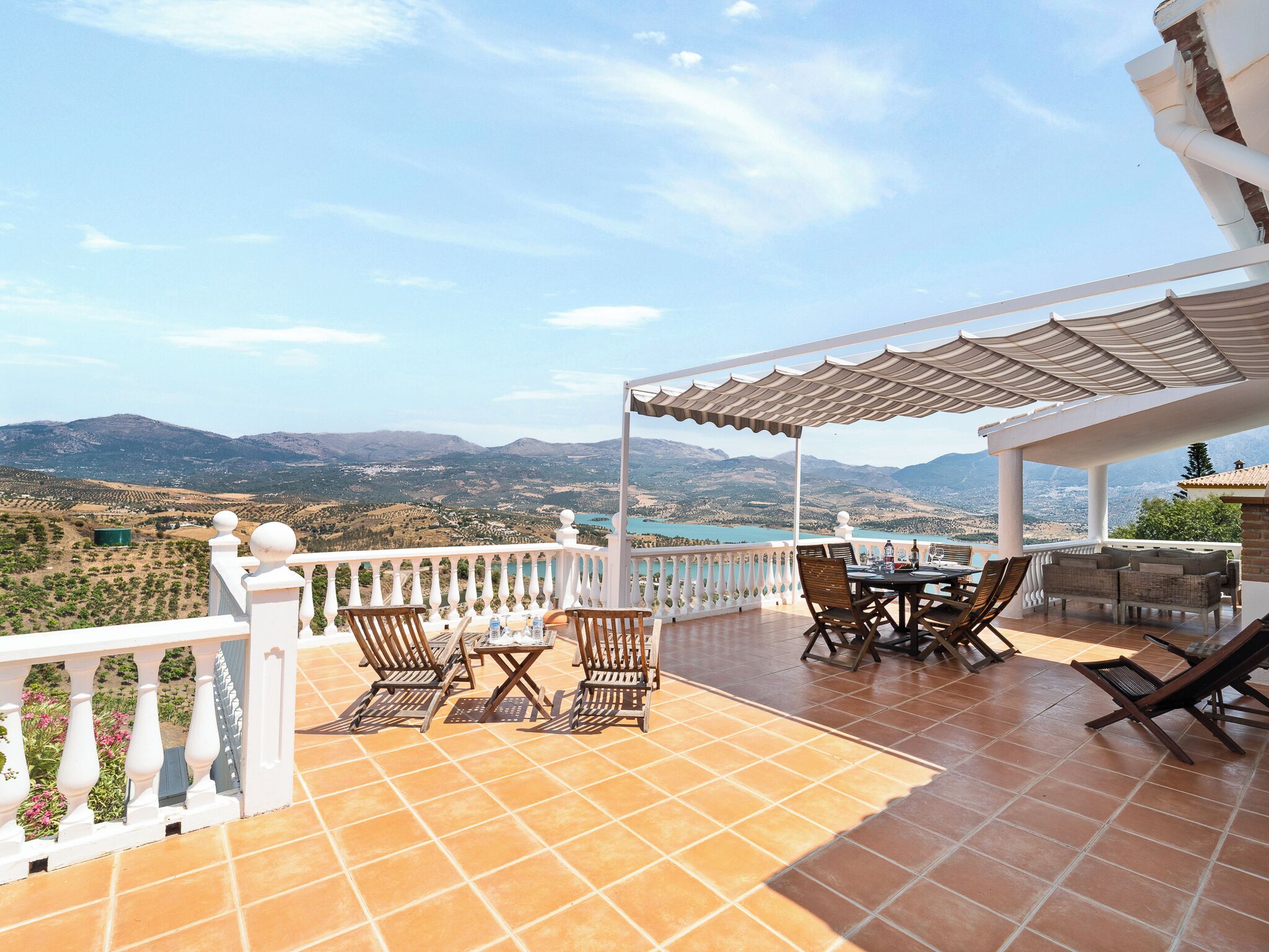 Eine Terrasse mit Tisch und Stühlen mit Blick auf eine gebirgige Landschaft.