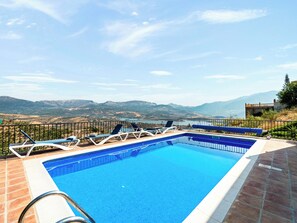 A swimming pool with lounge chairs and a view of distant mountains. - Casa Juan for 8 people, with a private pool, a patio with a grill, and a magnificent lake view (Viñuela)