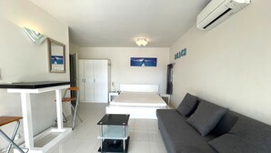 A hotel room with a bed, a sofa, a desk, and a cart. - 1-BR Villa with Terrace and Air Conditioning - Cap d'Agde (Cap d'Agde)