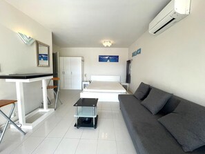 A hotel room with a bed, a sofa, a desk, and a cart. - 1-BR Villa with Terrace and Air Conditioning - Cap d'Agde (Cap d'Agde)