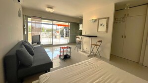 A modern bedroom with a large bed, a sofa, a desk with chairs, and a wardrobe. - 1-BR Villa with Terrace and Air Conditioning - Cap d'Agde (Cap d'Agde)