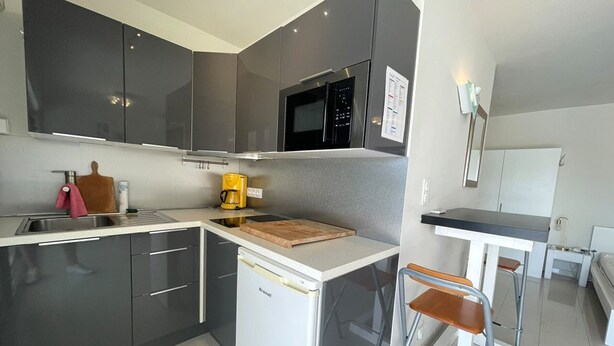A compact kitchen with a microwave, coffee maker, and a small island with a cutting board. - 1-BR Villa with Terrace and Air Conditioning - Cap d'Agde (Cap d'Agde)