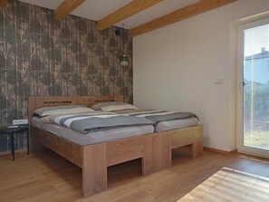 A bedroom with a wooden bed, a nightstand, and a window with blinds.