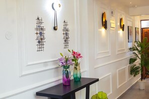 A hallway with decorative wall art, a black table with vases, and a potted plant. - Luxury 2-Bedroom Apartment in Nyali with Pool & Beach Access in Mombasa (Mombasa)