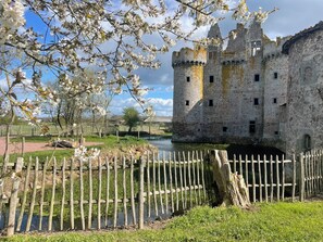A historic castle with a moat, surrounded by a wooden fence and blooming trees. - The Farmhouse at the Château de l'Ébaupinay (Argentonnay)
