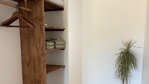 Um quarto com um armário de madeira, uma planta em vaso e uma parede branca.