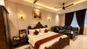 Ein Hotelzimmer mit einem großen Bett, zwei Deckenventilatoren, einem Sofa, einem Couchtisch und einem Gemälde an der Wand.