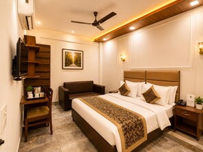 A hotel room with a bed, a desk, a chair, a television, and a ceiling fan. - Hotel Kasa Stays Near DTU Rohini (New Delhi)