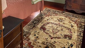 Een kamer met een bed, een kaptafel, een raam met kantgordijnen en een plafondventilator.