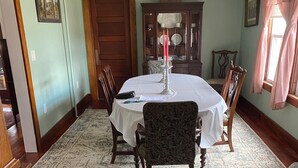 Een eetkamer met een ronde tafel, stoelen, een kroonluchter en een kamerbreed tapijt.