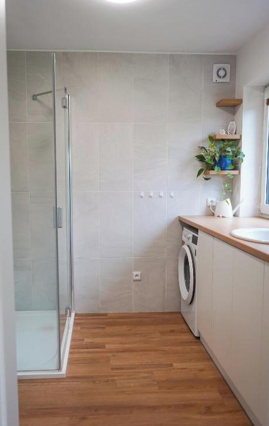 Une salle de bain moderne avec une douche à parois de verre, un lave-linge et un lavabo.
