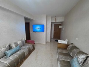 Ein Wohnzimmer mit zwei Sofas, einem Fernseher und einer Tür zu einem anderen Raum.