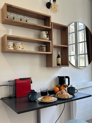 Eine Küche mit Holzböden, einer Kaffeemaschine und einer Frühstücksauslage mit Croissants und Orangen.
