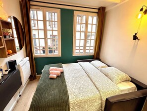 Ein Schlafzimmer mit einem Bett, einem Nachttisch, einer Kommode und einem Fenster mit Vorhängen.