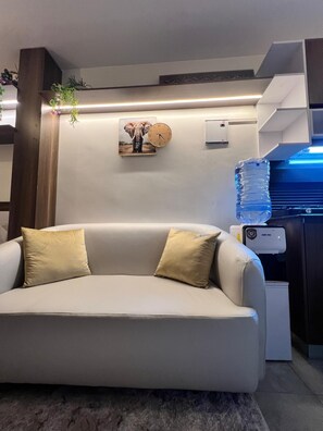 Ein modernes Wohnzimmer mit einer Couch, einer Wanduhr und einem Wasserspender.