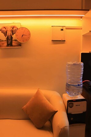 Une pièce comprenant un canapé, un distributeur d’eau, une horloge et un climatiseur fixé au mur.