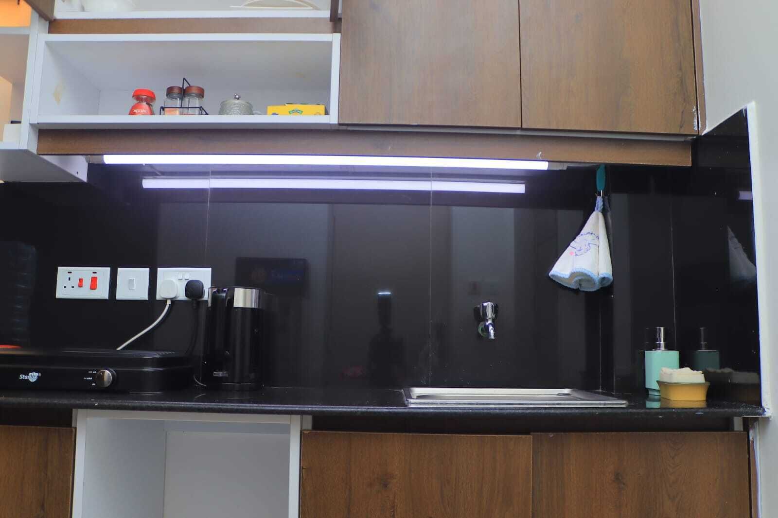 Una cocina con encimera negra, cafetera, lavabo y refrigerador pequeño.