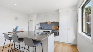 A modern kitchen with a central island, bar stools, a built-in oven, and a window with a view.