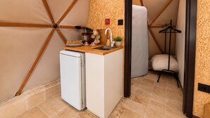 Una kitchenette compacta con refrigerador, lavamanos y una pequeña encimera.