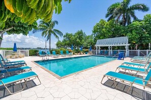 Ein Poolbereich mit blauen Liegestühlen, einem Pool und einer überdachten Sitzgelegenheit.