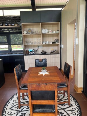 A dining area with a wooden table, four chairs, a decorative star centerpiece, and a bookshelf filled with various items. - 8 @ Mill Lane • Hartbeespoort Guesthouse • Hot Tub & Mountain Views (Hartbeespoort)