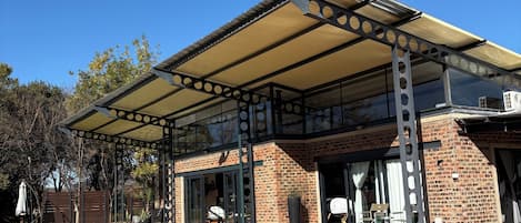 Un espace extérieur abrité comprenant une piscine, une terrasse circulaire en briques et une structure en forme de pergola.