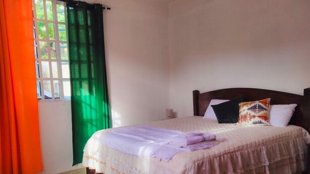 Une chambre à coucher avec un lit, des rideaux et une fenêtre.