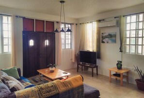 A living room with a sofa, a television, a coffee table, and a potted plant. - Hillside home with stunning sea views next to Roseau (Roseau)