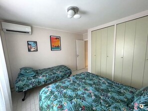 Ein Schlafzimmer mit zwei Einzelbetten, einem Kleiderschrank und zwei Wand-Klimaanlagen.
