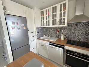 A kitchen with white cabinets, a stainless steel refrigerator, a patterned backsplash, and a wooden countertop. - Comfortable apartment with air conditioning - 6 guests (Argelès-sur-Mer)
