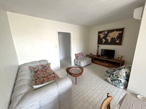 Ein Wohnzimmer mit einer Couch, einem Couchtisch und einem Fernseher.